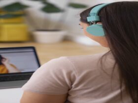 Pessoa conectada em chamada de vídeo com fones de ouvido coloridos, em ambiente doméstico